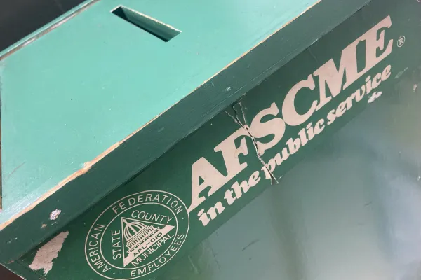 a photo shows an old green union ballot box with a vintage AFSCME bumper sticker on the front.