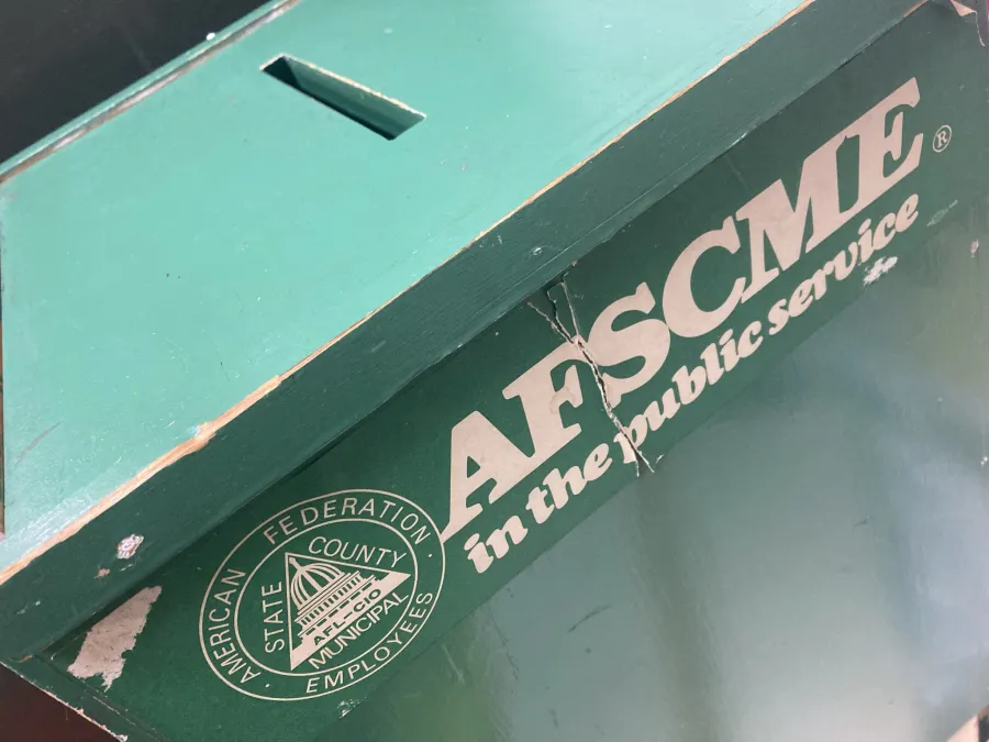 a photo shows an old green union ballot box with a vintage AFSCME bumper sticker on the front.